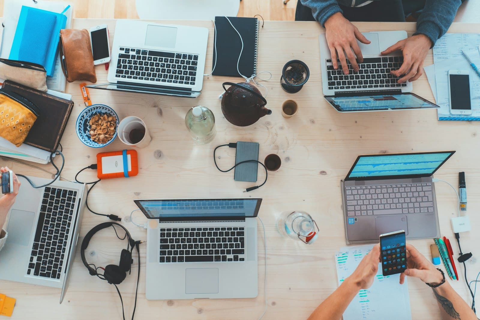 Team collaborating with laptops and technology tools across diverse business environments